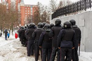 Polizisten in schwarzen Helmen warten auf den Befehl, die Demonstranten festzunehmen. foto
