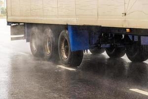 Trockener Lieferwagen, der sich tagsüber auf einer nassen Straße mit Spritzern bewegt foto