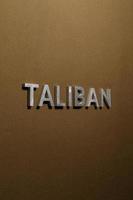 das wort taliban mit silbernen metallbuchstaben auf grobem khakifarbenem canvas-stoff foto