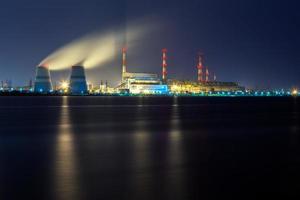altes thermisches 450-Megawatt-Kraftwerk nachts mit künstlichem See im Vordergrund foto