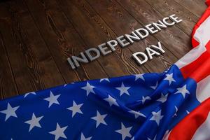 die worte unabhängigkeitstag auf brauner holzplankenoberfläche mit zerknitterter flagge der vereinigten staaten von amerika foto