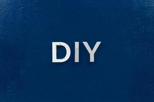 das kürzel diy - do it yourself - mit aluminiumbuchstaben auf dunkelblaue ebene fläche gelegt foto