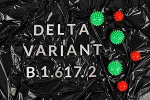 Wörter Delta-Variante b.1.617 mit silbernen Metallbuchstaben auf zerknittertem schwarzem Plastiktütenhintergrund in diagonaler Perspektive foto