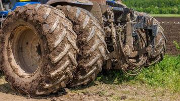 Schmutzige Doppelräder des Landwirtschaftstraktors auf der unbefestigten Straße am sonnigen Sommertag foto