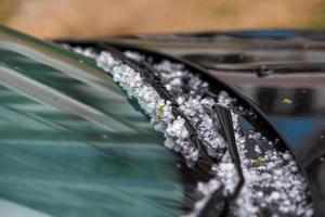 kleine hageleisbälle auf schwarzer autohaube nach schwerem sommersturm foto