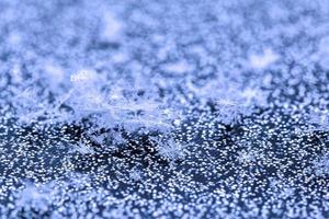 Schneeflocken auf glänzendem Oberflächenmakrohintergrund mit selektivem Fokus foto