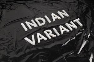 Wörter indische Variante mit silbernen Metallbuchstaben auf zerknittertem schwarzem Plastiktütenhintergrund in diagonaler Perspektive gelegt foto