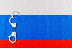 Geöffnete Handschellen aus silbernem Metall auf Vollbildhintergrund der russischen Flagge foto