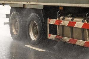 schwerer lkw, der tagsüber auf einer nassen straße mit spritzern fährt foto