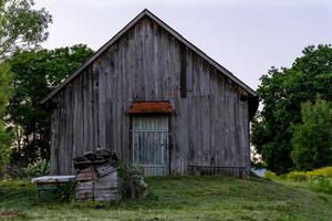 Alte Holzscheune auf dem Hof mit gemähtem Rasen am Sommerabend foto