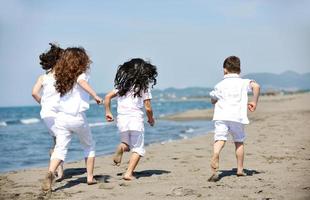 glückliche Kindergruppe, die am Strand spielt foto