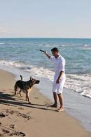 glückliche familie, die mit hund am strand spielt foto