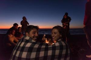 Paar genießt mit Freunden den Sonnenuntergang am Strand foto