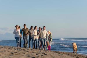 gruppe von freunden, die während des herbsttages am strand laufen foto