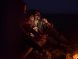 paar, das nachts mit freunden am strand genießt foto