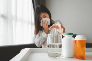 kranke asiatische Frau, die nach Medizin greift foto