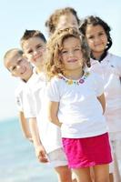 glückliche Kindergruppe, die am Strand spielt foto