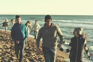 gruppe von freunden, die während des herbsttages am strand laufen foto