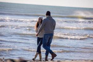 Liebendes junges Paar an einem Strand am sonnigen Herbsttag foto