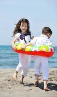 glückliche Kindergruppe, die am Strand spielt foto