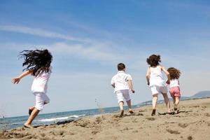 glückliche Kindergruppe, die am Strand spielt foto