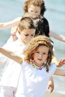 glückliche Kindergruppe, die am Strand spielt foto