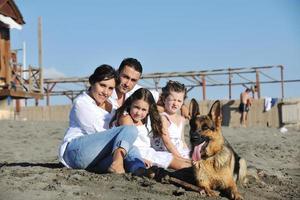 glückliche familie, die mit hund am strand spielt foto