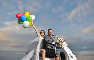 Gerade verheiratetes Paar am Strand fährt weißen Roller foto