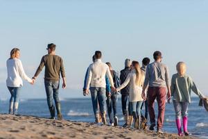 gruppe von freunden, die während des herbsttages am strand laufen foto