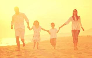 glückliche junge familie hat spaß am strand bei sonnenuntergang foto