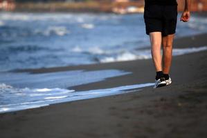 Mann läuft am Strand foto
