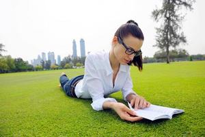 junge Frau, die ein Buch im Park liest foto