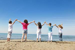 glückliche Kindergruppe, die am Strand spielt foto