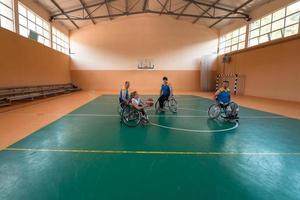 Behinderte Kriegsveteranen gemischte Rassen- und Alters-Basketballteams in Rollstühlen, die ein Trainingsspiel in einer Sporthalle spielen. Rehabilitations- und Inklusionskonzept für behinderte Menschen foto