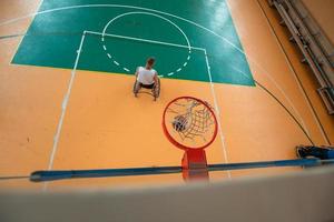 Abschleppfoto eines Kriegsveteranen, der Basketball in einer modernen Sportarena spielt. das Konzept des Sports für Menschen mit Behinderungen foto