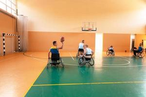 Behinderte Kriegsveteranen gemischte Rassen- und Alters-Basketballteams in Rollstühlen, die ein Trainingsspiel in einer Sporthalle spielen. Rehabilitations- und Inklusionskonzept für behinderte Menschen foto