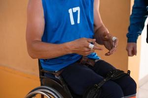 ein behinderter basketballspieler bereitet sich auf ein spiel vor, während er im rollstuhl sitzt.vorbereitungen für ein professionelles basketballspiel. das Konzept des Behindertensports foto