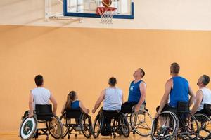 Behinderte Kriegsveteranen im Einsatz beim Basketballspielen auf einem Basketballplatz mit professioneller Sportausrüstung für Behinderte foto