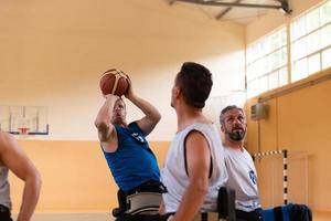 behinderte kriegsveteranen in rollstühlen mit professioneller ausrüstung spielen basketballmatch in der halle.das konzept des sportes mit behinderungen foto