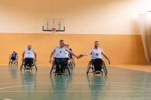 ein Team von Kriegsveteranen in Rollstühlen, die Basketball spielen und die in einem Spiel gewonnenen Punkte feiern. High-Five-Konzept foto