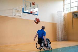ein kriegsbeschädigter im rollstuhl trainiert mit einem ball in einem basketballverein beim training mit professionellen sportgeräten für behinderte. das Konzept des Sports für Menschen mit Behinderungen foto
