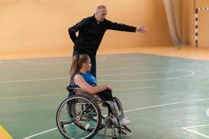 Ein Sportbasketballtrainer erklärt einer behinderten Frau im Rollstuhl, welche Position sie während eines Spiels einnehmen soll foto