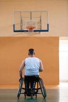 ein kriegsbeschädigter im rollstuhl trainiert mit einem ball in einem basketballverein beim training mit professionellen sportgeräten für behinderte. das Konzept des Sports für Menschen mit Behinderungen foto