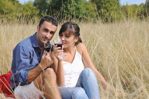 glückliches Paar, das ein Picknick auf dem Land im langen Gras genießt foto