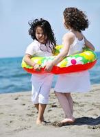 glückliche Kindergruppe, die am Strand spielt foto