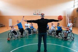 der Auswahltrainer der Basketballmannschaft mit Behinderung steht vor den Spielern und zeigt ihnen die Dehnübungen vor Trainingsbeginn foto