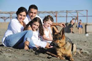 glückliche familie, die mit hund am strand spielt foto
