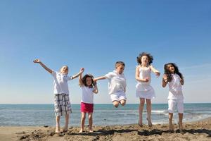 glückliche Kindergruppe, die am Strand spielt foto