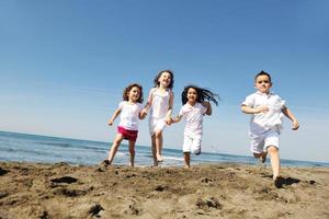 glückliche Kindergruppe, die am Strand spielt foto