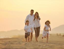 glückliche junge familie hat spaß am strand bei sonnenuntergang foto